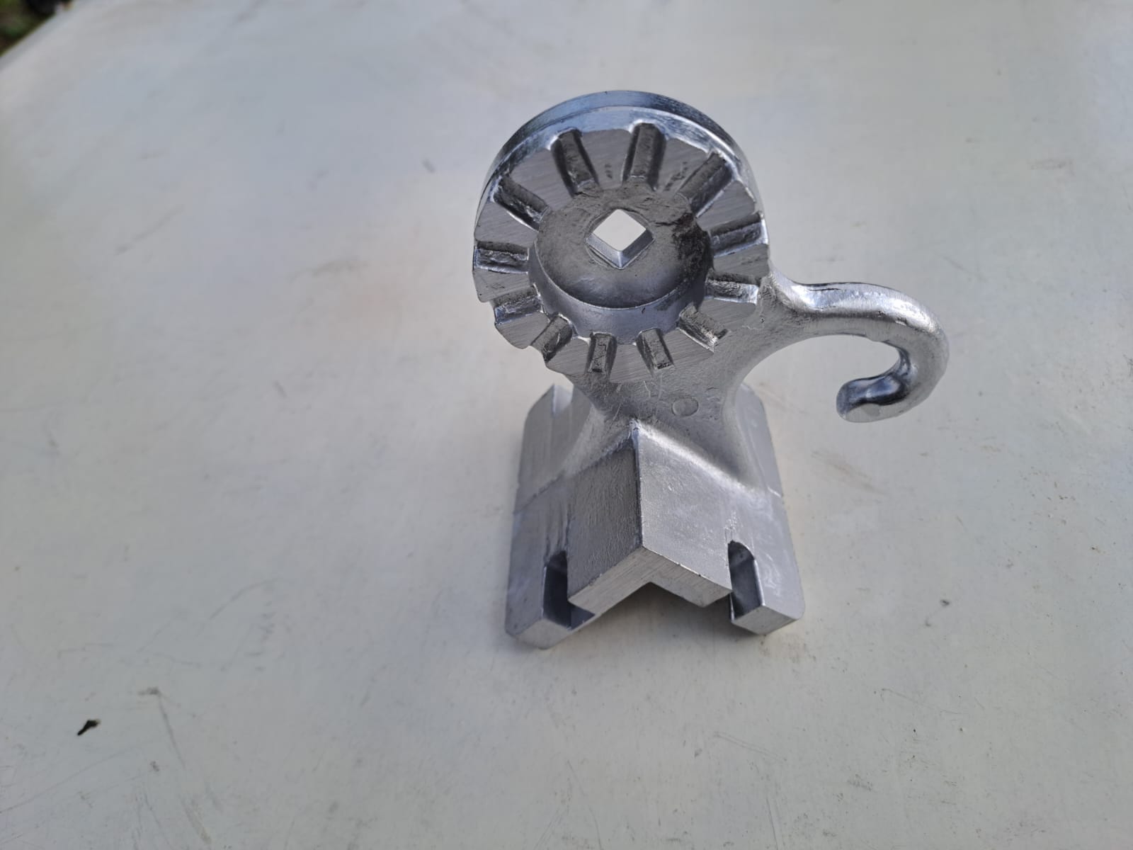 Na zdjęciu widoczny jest odlew aluminiowy wykonany kokilowo jednego z trzech elementów kompletu odlewów wykorzystywanych przy produkcji markiz balkonowych. Odlew ten jest przedstawiony po obróbce mechanicznej. Jest to element mocowany do balustrady przy montażu markizy, zaś jego górna część służy napinani linki prowadzącej za pomocą haka i zapobieganiu niepożądanego rozwijania się markizy za pomocą pierścienia z rowkami ustawionymi wzdłuż promienia na całym obwodzie zewnętrznego pierścienia.