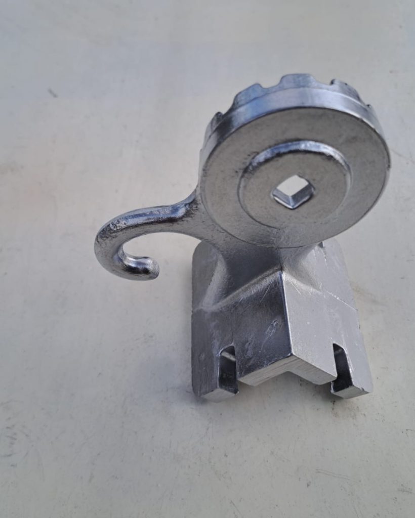 IMG-20240313-WA0002 Na zdjęciu widoczny jest odlew aluminiowy wykonany kokilowo jednego z trzech elementów kompletu odlewów wykorzystywanych przy produkcji markiz balkonowych. Odlew ten jest przedstawiony po obróbce mechanicznej. Jest to element mocowany do balustrady przy montażu markizy, zaś jego górna część służy napinani linki prowadzącej za pomocą haka i zapobieganiu niepożądanego rozwijania się markizy za pomocą pierścienia z rowkami ustawionymi wzdłuż promienia na całym obwodzie zewnętrznego pierścienia.