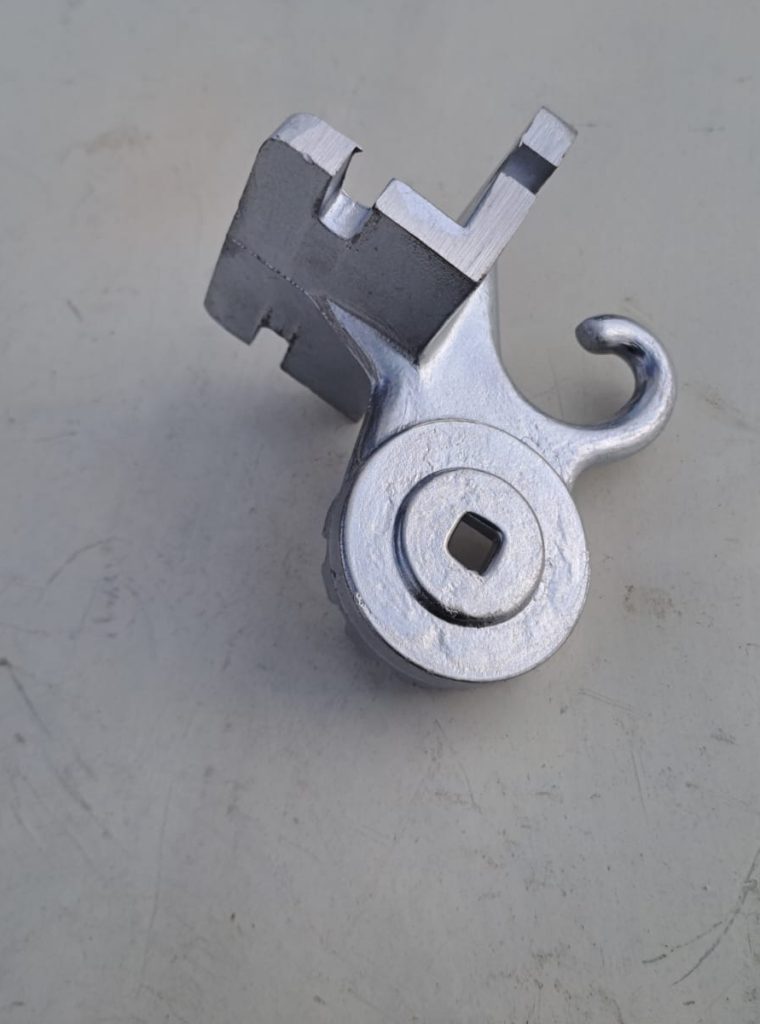 IMG-20240313-WA0005 Na zdjęciu widoczny jest odlew aluminiowy wykonany kokilowo jednego z trzech elementów kompletu odlewów wykorzystywanych przy produkcji markiz balkonowych. Odlew ten jest przedstawiony po obróbce mechanicznej. Jest to element mocowany do balustrady przy montażu markizy, zaś jego górna część służy napinani linki prowadzącej za pomocą haka i zapobieganiu niepożądanego rozwijania się markizy za pomocą pierścienia z rowkami ustawionymi wzdłuż promienia na całym obwodzie zewnętrznego pierścienia.